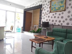 a living room with a green couch and a table at Kenangan Guest House in Sabang