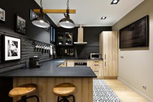 cocina con paredes negras y taburetes de madera en Sagrada266 by chicStays, en Barcelona