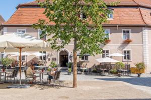 uma árvore com pessoas sentadas numa mesa em frente a um edifício em Romantica Hotel Blauer Hecht em Dinkelsbühl