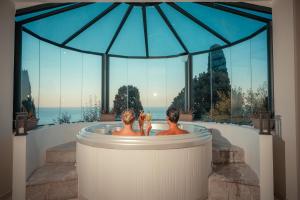 Dos hombres en una bañera con vistas al océano en Grand Hotel San Pietro, en Taormina