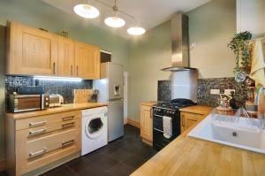 a kitchen with wooden cabinets and a washer and dryer at Slipway cottage 21 Picton road in Milford Haven