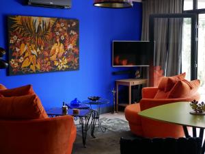 a blue living room with orange chairs and a tv at Suite 24 in Aubenas