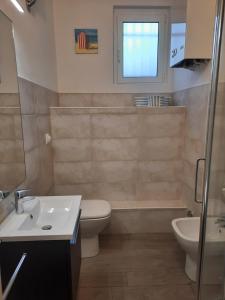a bathroom with a toilet and a sink and a window at Appartamento Blu in Deiva Marina