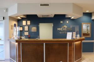 a lobby of a mochiod by winery with a counter at Microtel Inn & Suites by Wyndham Columbus Near Fort Moore in Columbus