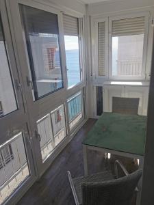 a room with a table and chairs and windows at Beach front Esther 4 villajoyosa in Villajoyosa