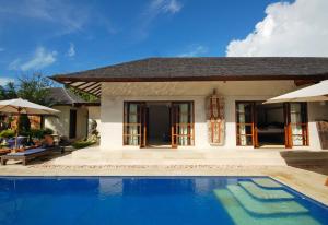 a villa with a swimming pool in front of a house at Frangipani Beach Hotel in Lovina +38 photos