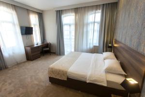 a bedroom with a bed and a desk and windows at Old Meidan Tbilisi By Urban Hotels in Tbilisi City