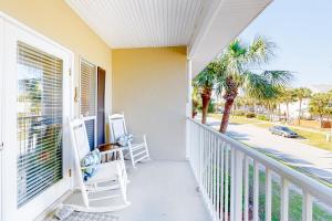 a balcony with two chairs and a palm tree at Caribbean Dunes #226 in Destin
