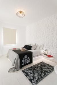 a white bedroom with a bed and a black and white rug at Naxos Earth Suites in Mikri Vigla