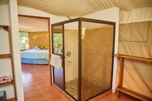 a glass shower in a room with a bed at Manoas in Uvita