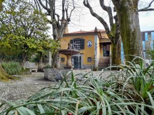 a yellow house with a fountain in front of it at Camelia Rooms in Guimarães