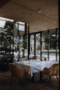 a dining room with a table and chairs and windows at Parkhotel Egerner Höfe in Rottach-Egern