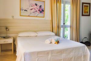 1 dormitorio con 1 cama blanca y 2 toallas enrolladas en LOCAR- IN GRAMADO Wald Haus Centro, en Gramado