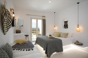 a white bedroom with a bed and a window at Naxos Earth Suites in Mikri Vigla