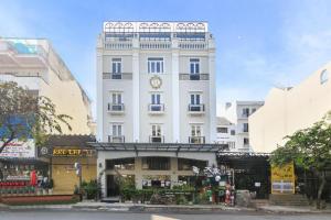 a tall white building with a clock on it at Sabina Residence - Stellar Boutique Hotel in Ho Chi Minh City