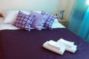 Una cama morada con almohadas y toallas. en Apartments Vera, en Okuklje