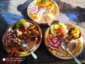 three plates of food on a table with spoons at Patlekhet Eco Farmhouse in Dhulikhel +46 photos