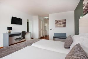 a hotel room with a white bed and a desk at Olé Tropical Tenerife Adults Only in Playa de las Americas
