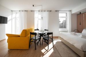 una camera con un tavolo, una sedia gialla e un letto di Guesthouse diWINE a Merano