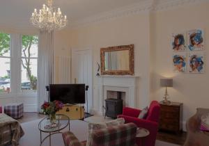Il comprend un salon avec une cheminée et une télévision. dans l'établissement Stockbridge Townhouse - The Edinburgh Address, à Édimbourg