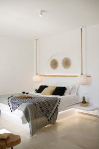 a white bedroom with a bed and two pendant lights at Naxos Earth Suites in Mikri Vigla