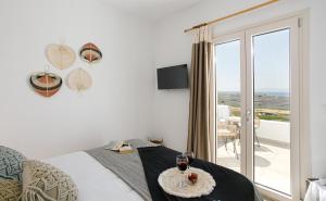 a bedroom with a bed with a table with two glasses of wine at Naxos Earth Suites in Mikri Vigla