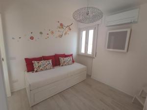 a white room with a couch with red pillows at Casa Celeste in San Benedetto del Tronto