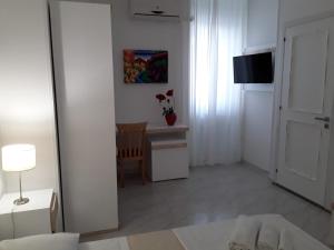Habitación blanca con mesa y espejo. en Porto Cesareo Hotel, en Porto Cesareo