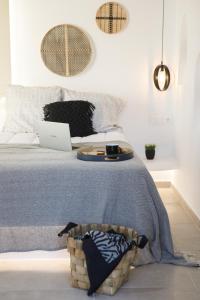Una cama con ordenador portátil y una cesta. en Naxos Earth Suites en Mikri Vigla