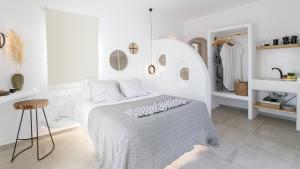 a white bedroom with a bed and a stool at Naxos Earth Suites in Mikri Vigla