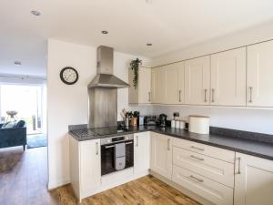 a kitchen with white cabinets and a stove top oven at Y Ty Pren in Brynteg