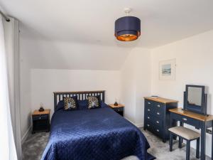 een slaapkamer met een blauw bed en een televisie bij Y Ty Pren in Brynteg