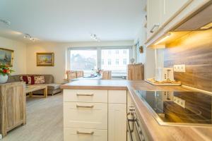 een keuken met witte kasten en een woonkamer bij Haus Sola Bona Sola Bona 1 in Westerland