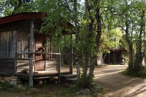 a small wooden cabin with a fence and trees at Tankavaara Gold Village in Tankavaara
