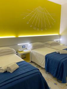 a hotel room with two beds and a yellow wall at Hotel La Meridiana in Sorrento