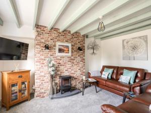 a living room with a couch and a brick wall at Crud Y Mor in Llanfairfechan