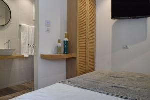 ein Bad mit einem Waschbecken und ein Bett in einem Zimmer in der Unterkunft Meltemi by Manthos Hotels in Skiathos-Stadt
