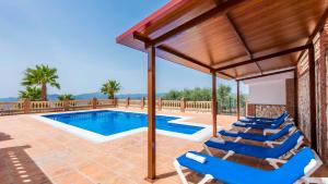 une piscine avec des chaises longues bleues et un pavillon dans l'établissement Finca Cerro Alcolea Periana by Ruralidays, à Periana