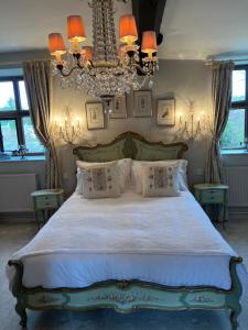 a bedroom with a large bed with a chandelier at Pytts House Boutique Bed & Breakfast in Burford