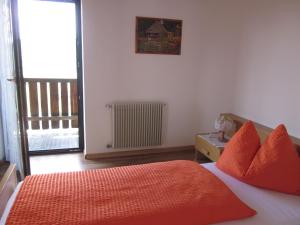 a bedroom with a bed with orange pillows and a window at Gasthof zum Roessl in San Genesio Atesino
