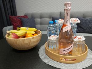 eine Flasche Champagner und eine Schale Obst auf dem Tisch in der Unterkunft Wizjonerów Luxury Apartment & Garage in Krakau