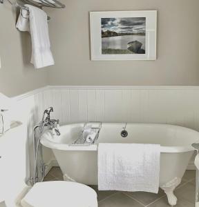 La salle de bains est pourvue d'une baignoire blanche et de toilettes. dans l'établissement Auberge Glengarry Inn, The Mystic, 