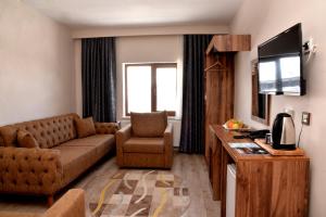 een woonkamer met een bank en een tv in een kamer bij Zümrüt Palas Otel in Erciyes