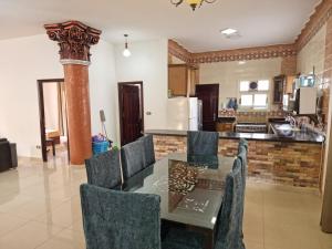 una cucina e una sala da pranzo con tavolo e sedie in vetro di فيلا العيلة Villa L-3eela a Abû Zeira