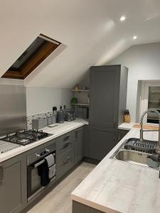 a kitchen with a sink and a stove top oven at Danbury Lodge Penthouse in Matlock