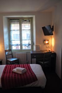 um quarto de hotel com uma cama, uma secretária e uma janela em HOTEL DES VOYAGEURS em Pont-de-Roide