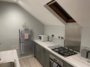 a kitchen with a stove and a microwave at Danbury Lodge Penthouse in Matlock