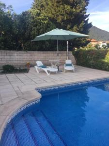 two chairs and an umbrella next to a swimming pool at Casa Cuesta del Reloj in Piedralaves
