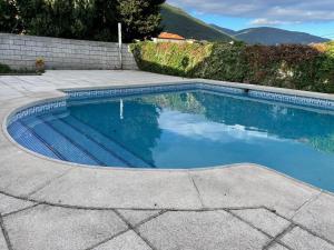 a swimming pool with blue water in a yard at Casa Cuesta del Reloj in Piedralaves