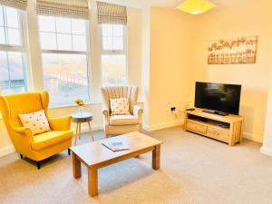 sala de estar con 2 sillas y TV de pantalla plana en Ilkley Apartment with Parking, en Ilkley